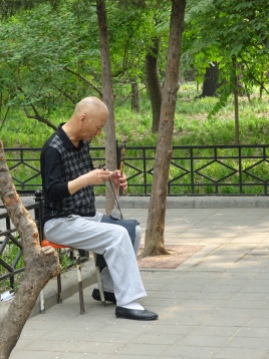 A man playing a very shrill instrument with one string and a bow